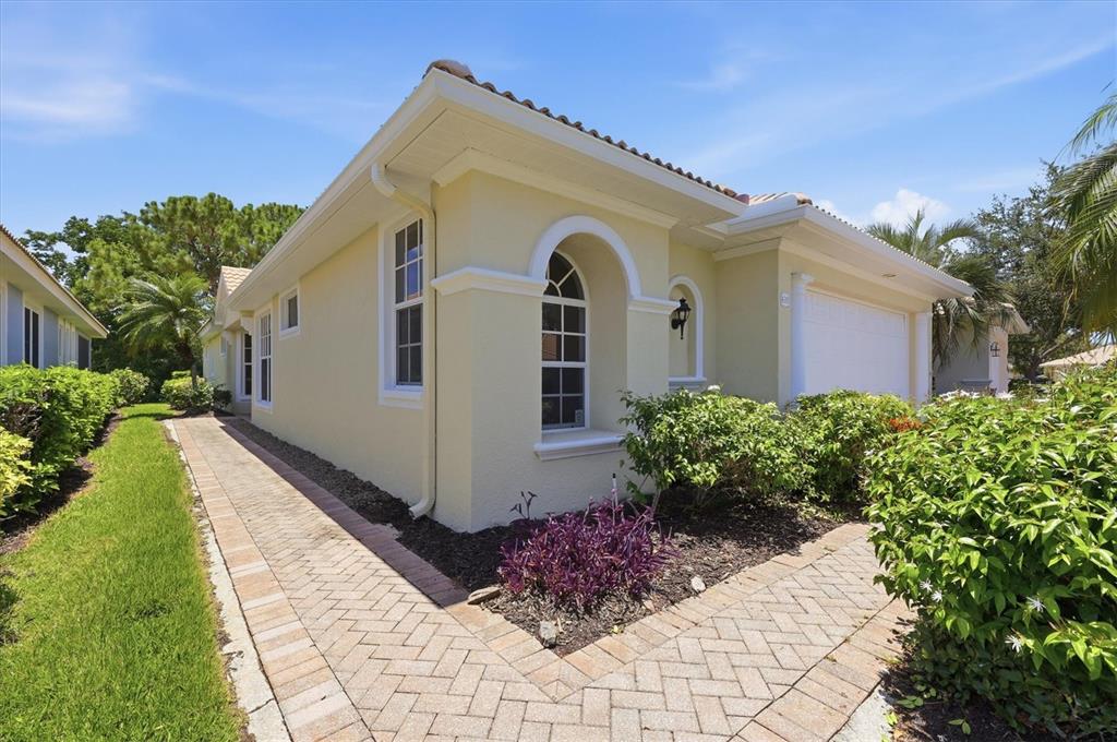 A single-story house with yellow stucco walls, a tiled roof, and a brick paver walkway — 4315 REFLECTIONS PARKWAY, SARASOTA, FL