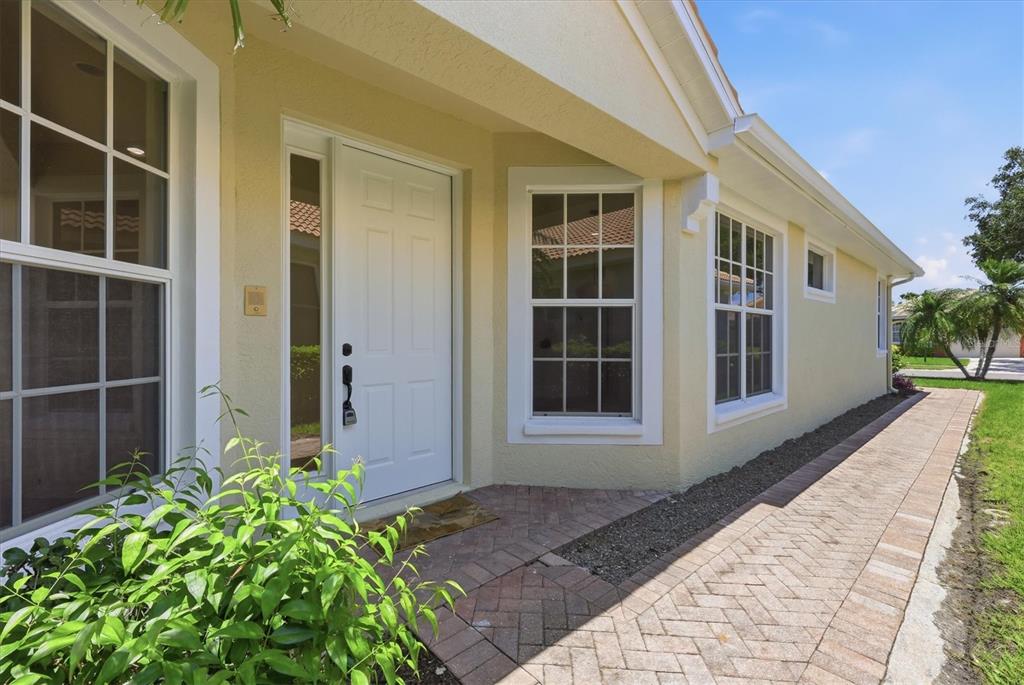 A yellow house exterior features a white front door, brick walkway, and multiple windows — 4315 REFLECTIONS PARKWAY, SARASOTA, FL