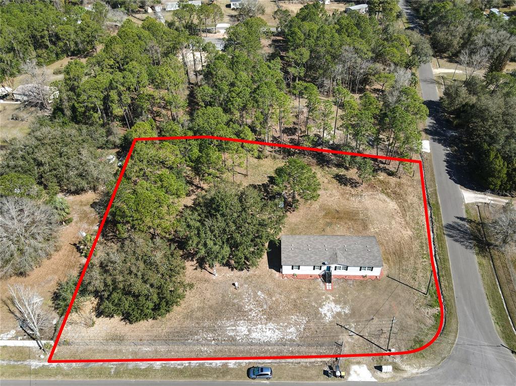 An aerial view shows a single-story house situated on a large, partially wooded lot — 3564 REAGAN BOULEVARD, LAKE WALES, FL