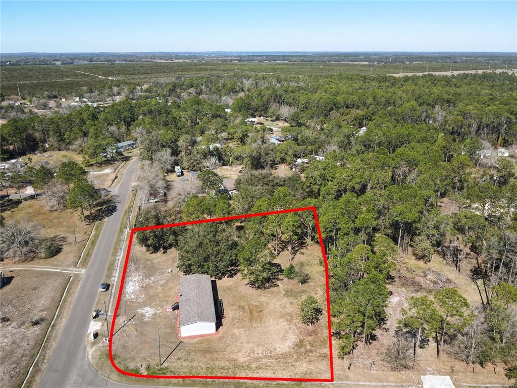 An aerial view shows a single-story house situated on a large, partially wooded lot — 3564 REAGAN BOULEVARD, LAKE WALES, FL