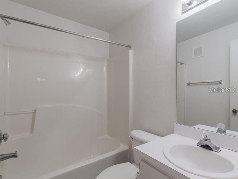 A bathroom features a white vanity, a toilet, and a shower-tub combination with white walls — 4000 SW 23RD STREET UNIT 4-103 #3, GAINESVILLE, FL