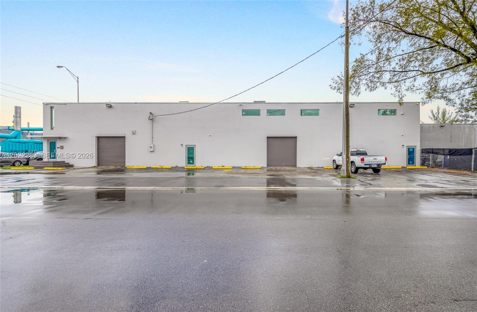A white industrial building features two roll-up doors, three entry doors, and a parking lot — 7550 W 2nd Ct, Hialeah FL 33014, HIALEAH, FL