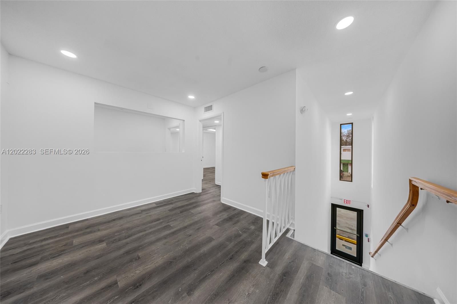 An indoor landing features dark wood-look flooring, white walls, and a staircase with railings — 7550 W 2nd Ct, Hialeah FL 33014, HIALEAH, FL