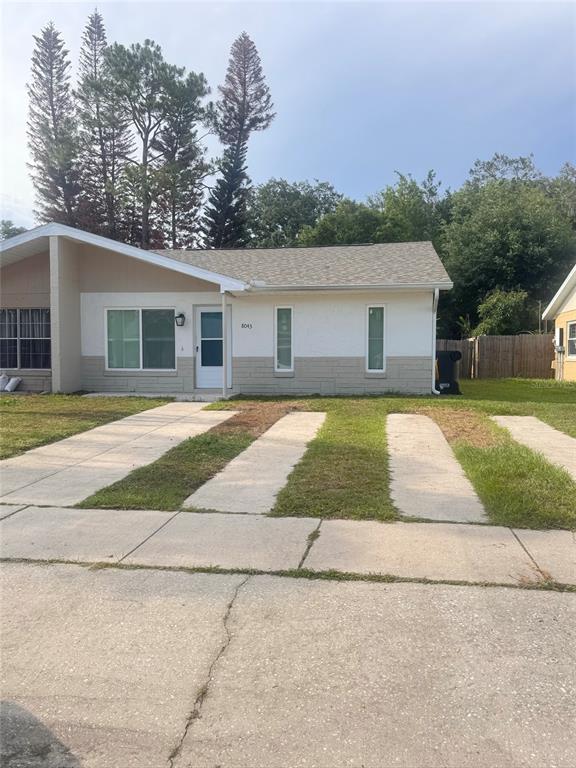 A single-story house with a white and tan exterior features a concrete driveway and lawn — 8043 PUFFIN DRIVE, ORLANDO, FL