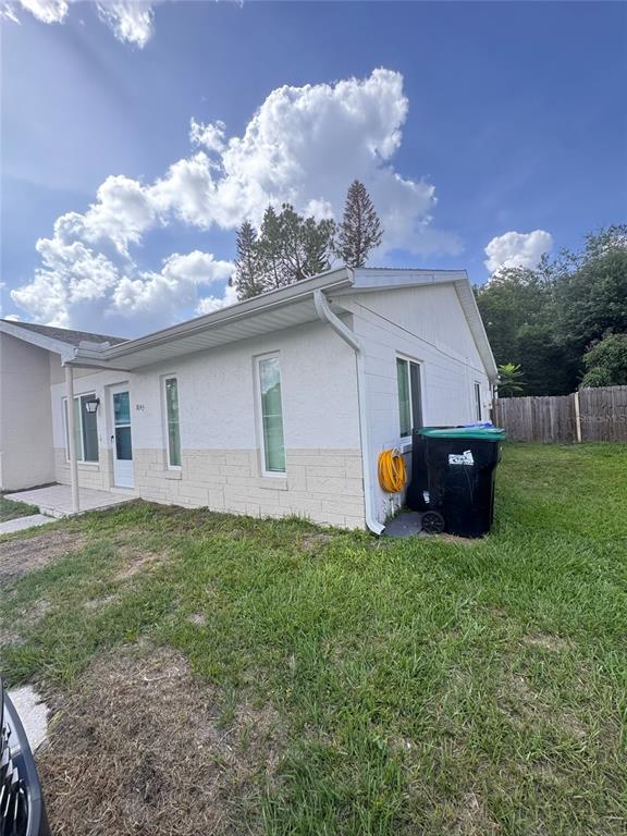 A white, single-story house with a concrete block base and a black trash bin outside — 8043 PUFFIN DRIVE, ORLANDO, FL