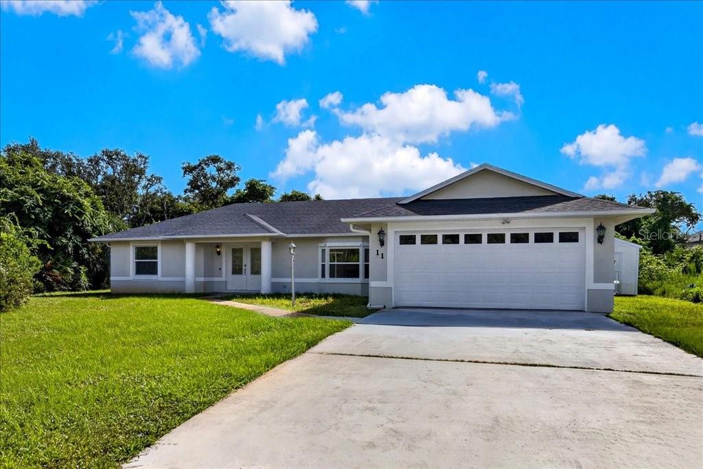 A single-story house with a white garage, gray siding, and a front lawn — 11 SWEET BAY DRIVE, PALM COAST, FL