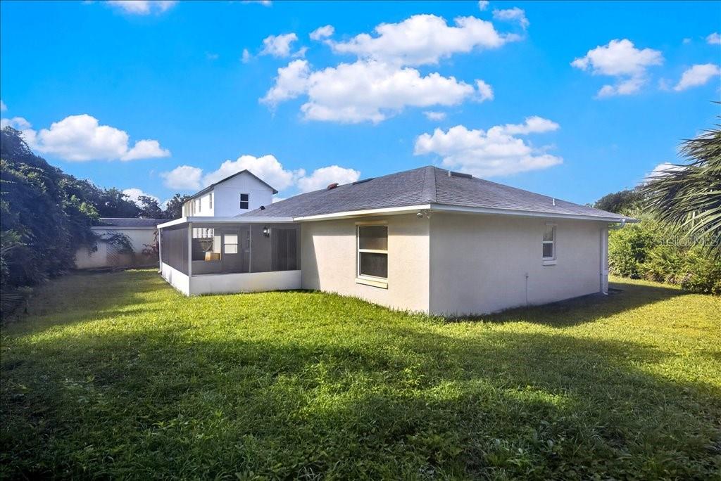 The exterior of a single-story house with a screened-in porch and a grassy backyard — 11 SWEET BAY DRIVE, PALM COAST, FL