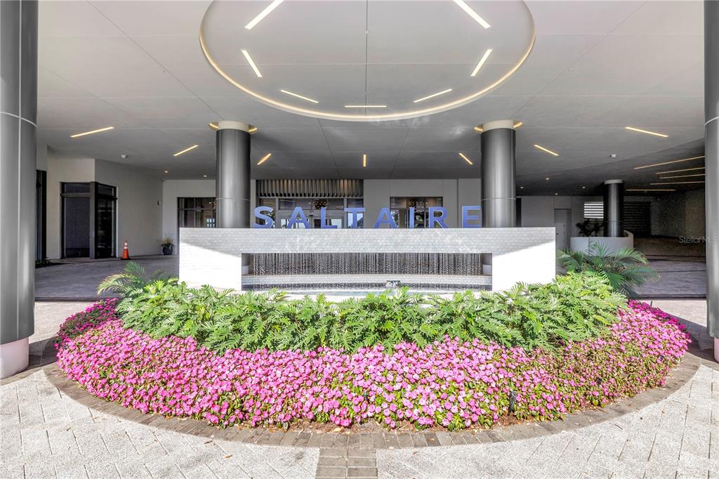 A modern building entrance features a circular ceiling light, a water fountain, and pink flowers — 301 1ST STREET S UNIT 2604, ST PETERSBURG, FL