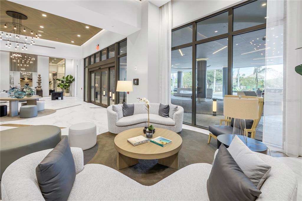 A modern lobby features curved sofas, a round coffee table, and floor-to-ceiling windows — 301 1ST STREET S UNIT 2604, ST PETERSBURG, FL