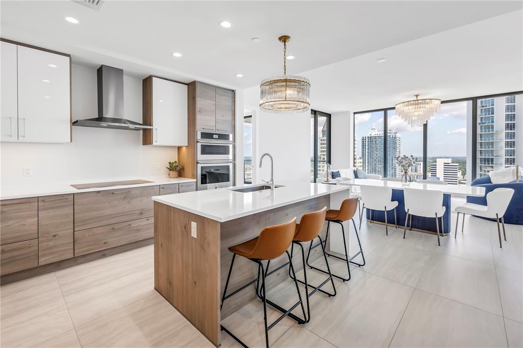 A modern kitchen features wood-toned cabinetry, white countertops, a central island, and floor-to-ceiling windows — 301 1ST STREET S UNIT 2604, ST PETERSBURG, FL