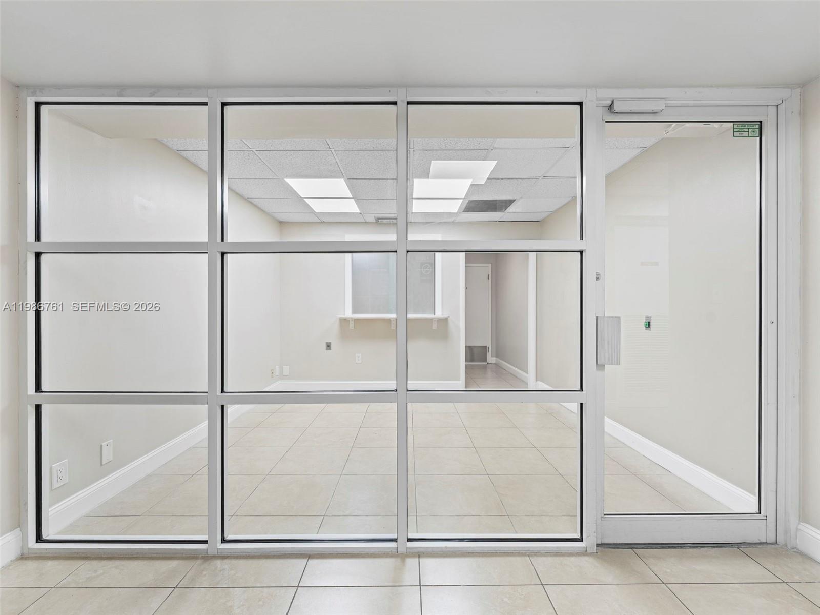 An office space features a glass-paneled wall, a glass door, and light-colored tile flooring — 1312 SW 27th Ave, Miami FL 33145, MIAMI, FL