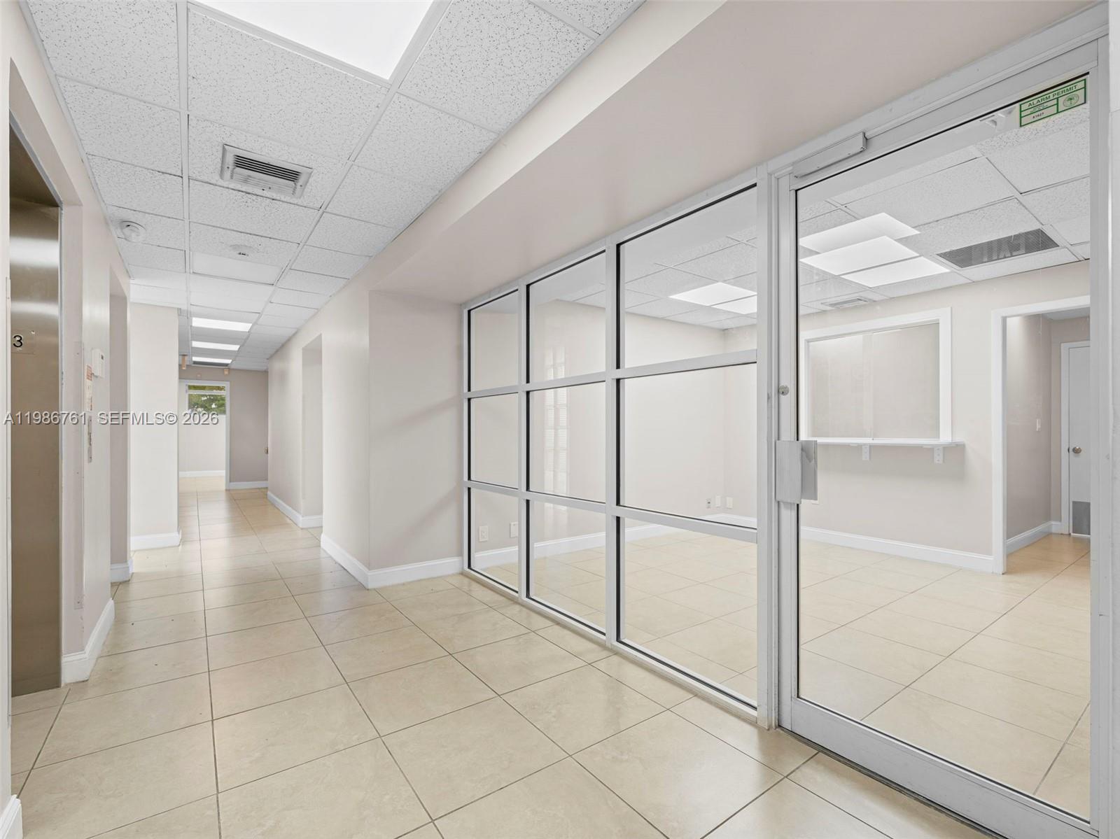 A hallway leads past a glass-walled office with tile flooring and a drop ceiling — 1312 SW 27th Ave, Miami FL 33145, MIAMI, FL