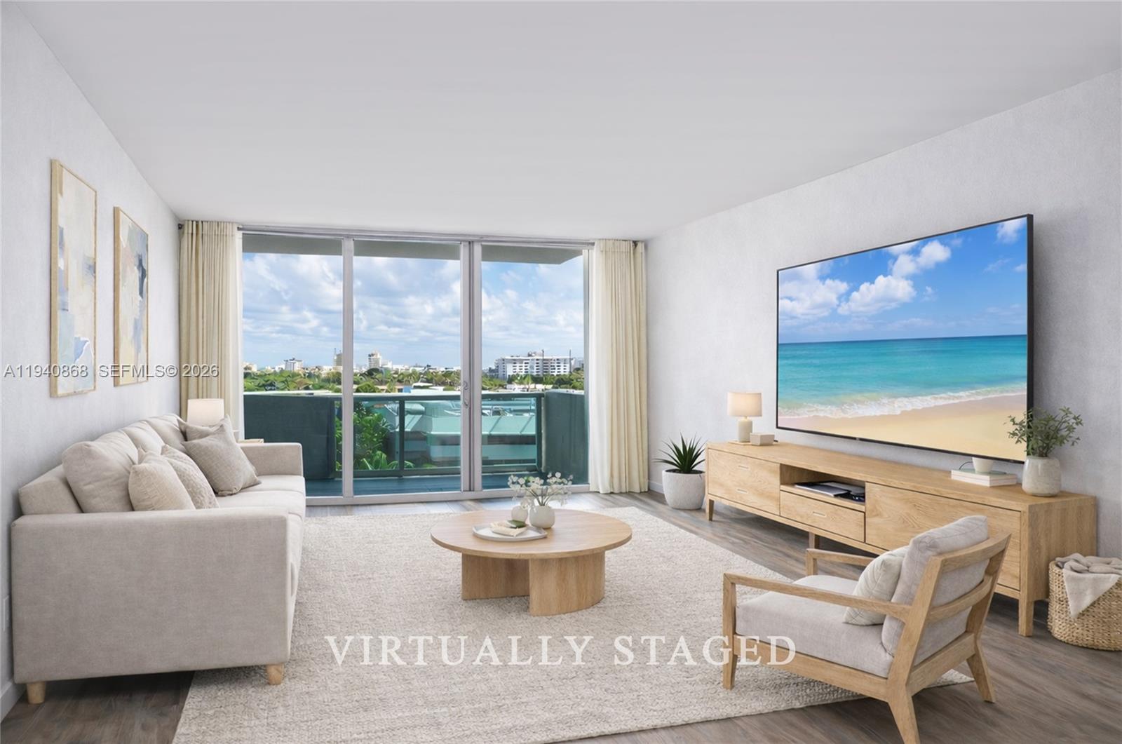 A living room with light wood furniture, a beige sofa, and a balcony with city views — 1200 West Ave # 708, Miami Beach FL 33139, MIAMI BEACH, FL