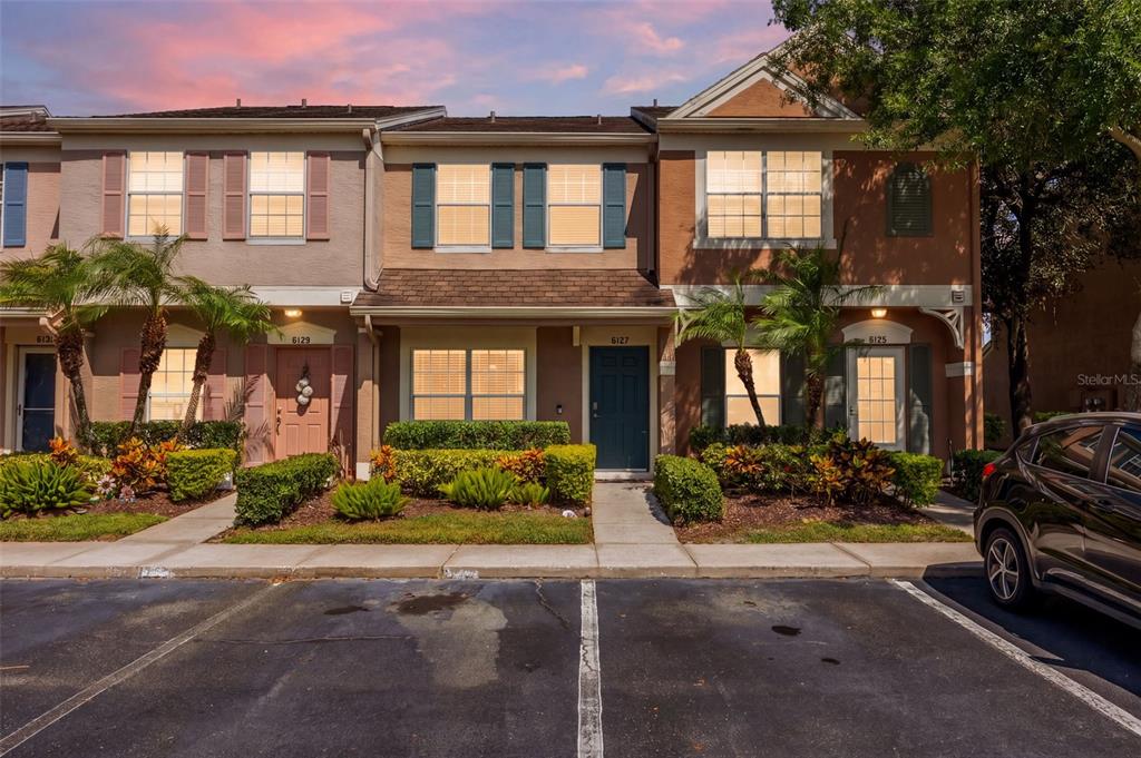 A row of three two-story townhouses with brown stucco facades and a parking lot — 6127 BAYSIDE KEY DRIVE, TAMPA, FL