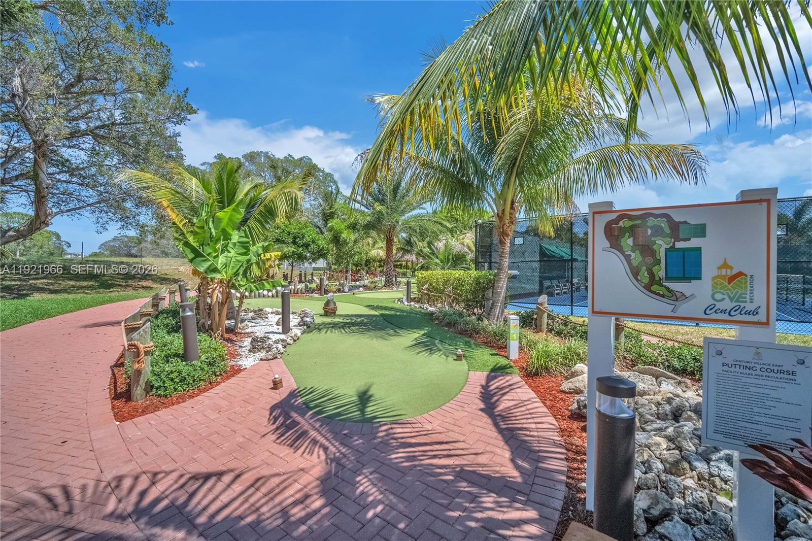 A putting course features a brick walkway, palm trees, and a facility information sign — 244 Durham F # 244, Deerfield Beach FL 33442, DEERFIELD BEACH, FL