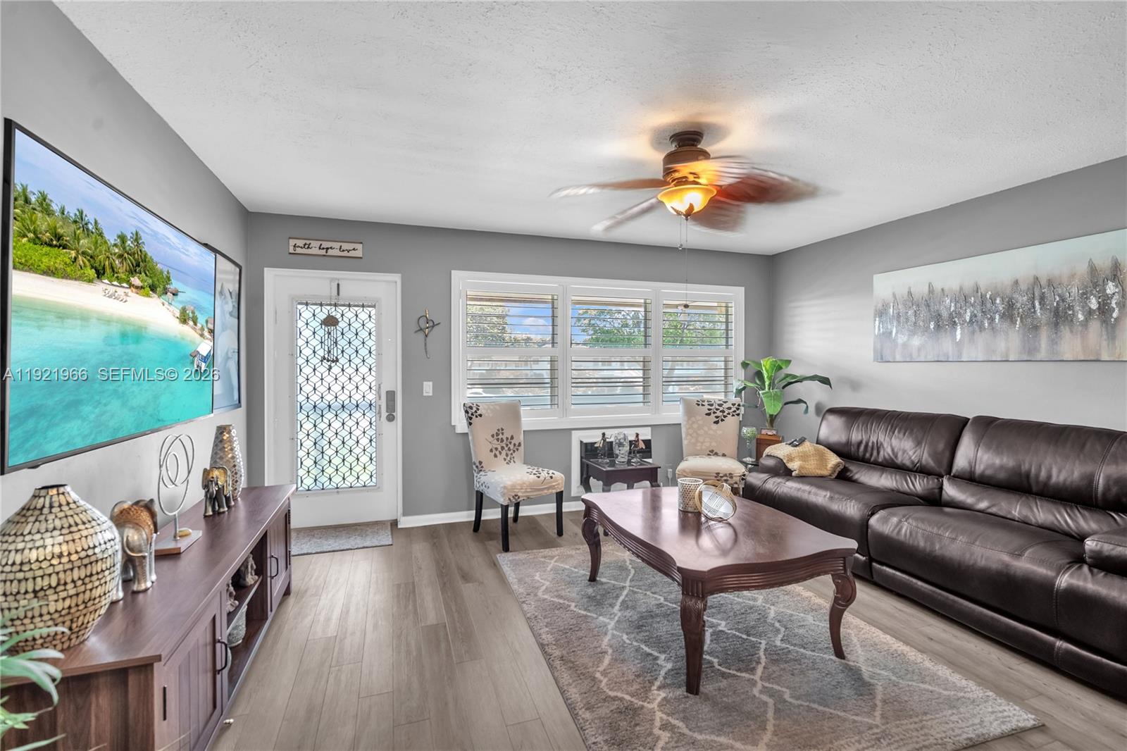 A living room features gray walls, wood-look flooring, a leather sofa, and a ceiling fan — 244 Durham F # 244, Deerfield Beach FL 33442, DEERFIELD BEACH, FL
