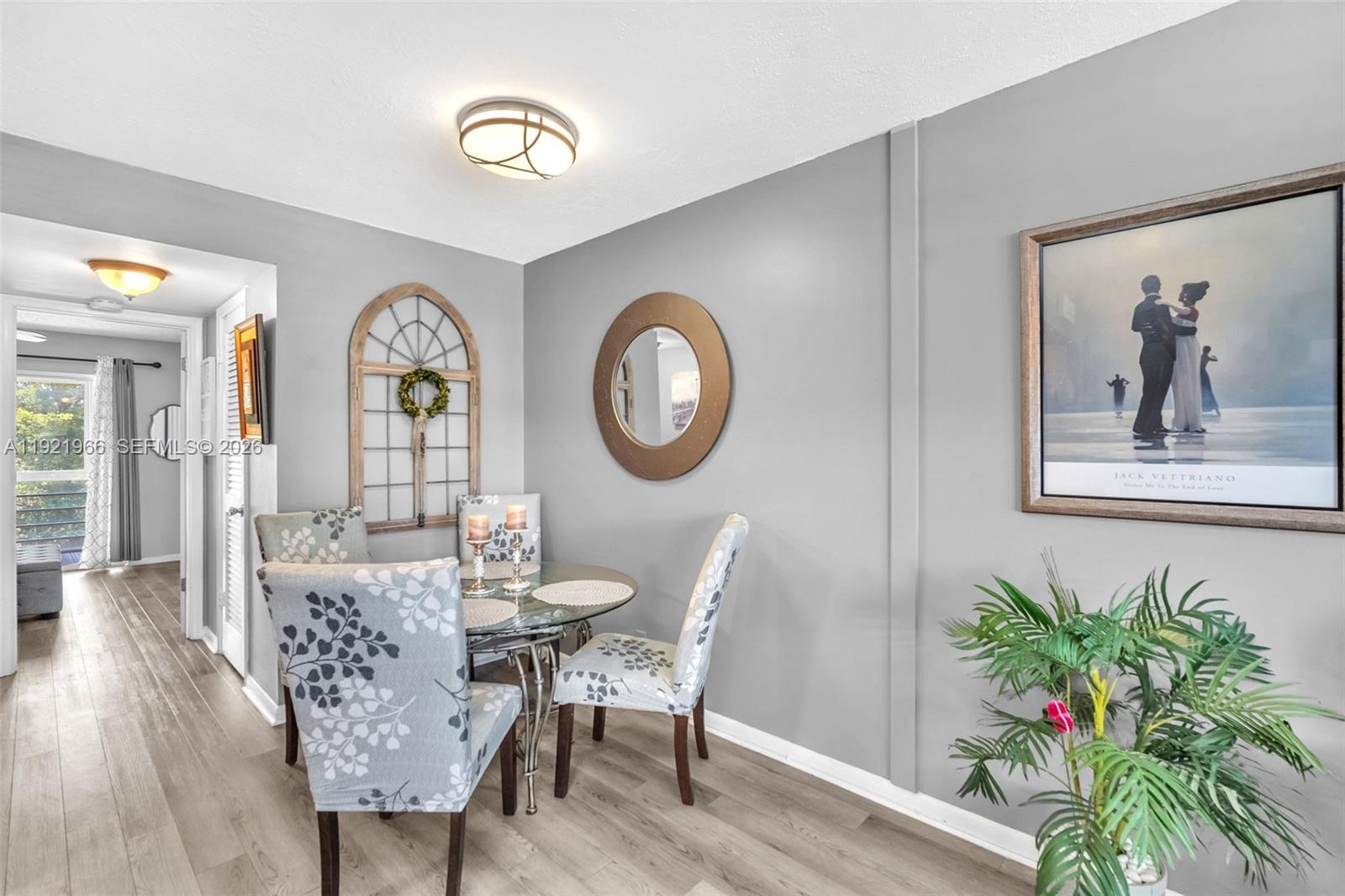 A dining area features a glass table, patterned chairs, a round mirror, and wall art — 244 Durham F # 244, Deerfield Beach FL 33442, DEERFIELD BEACH, FL