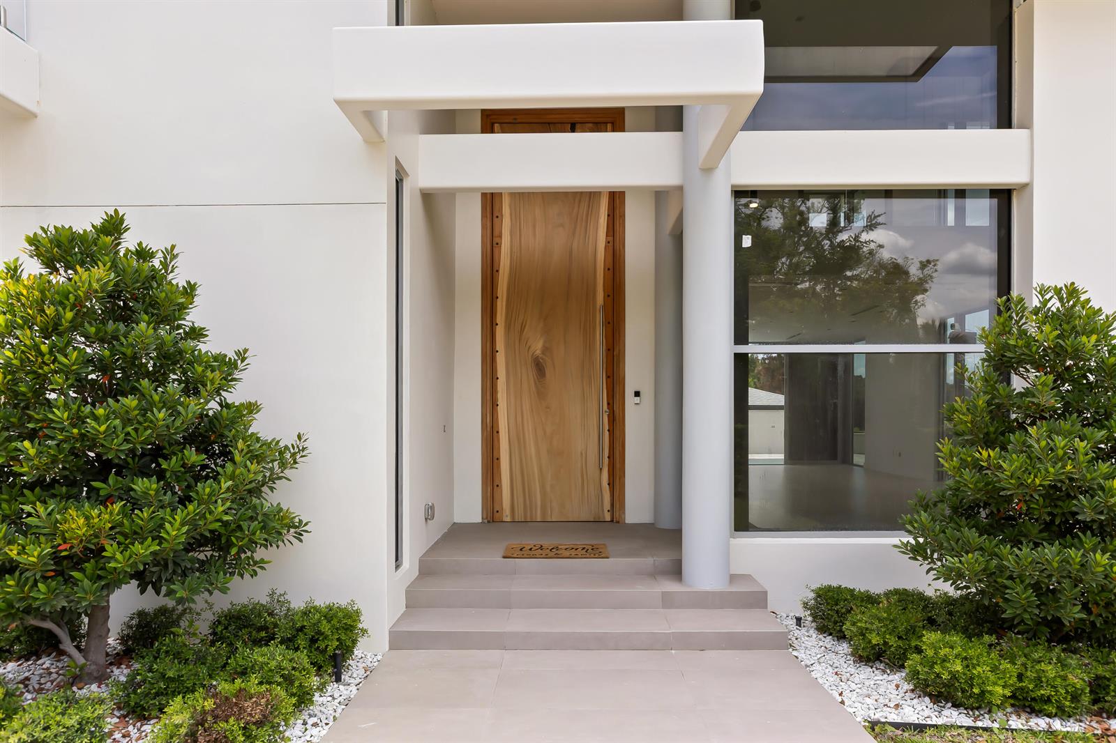 The exterior entrance features a natural wood door, concrete steps, and surrounding landscaping — 2661 Via Tuscany, Winter Park FL 32789, WINTER PARK, FL