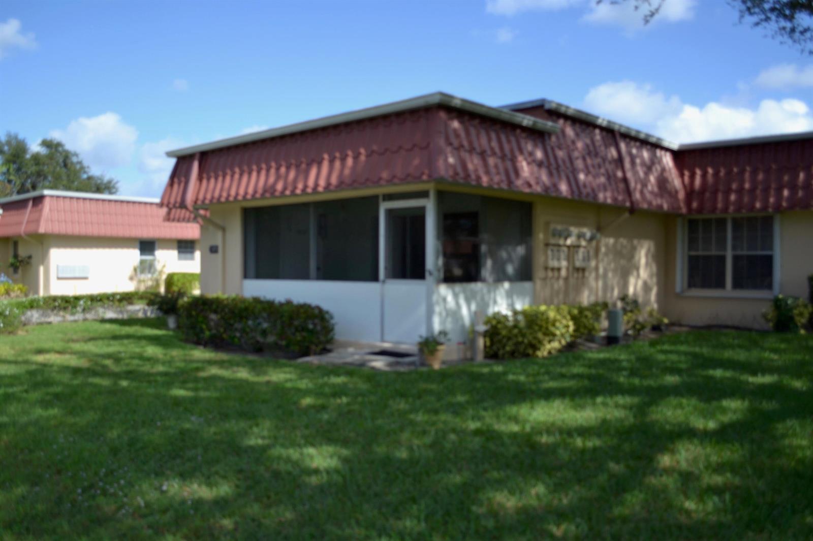 A single-story building with a red metal roof, beige stucco walls, and a front walkway — 570 Laconia Circle, Lake Worth FL 33467, LAKE WORTH, FL