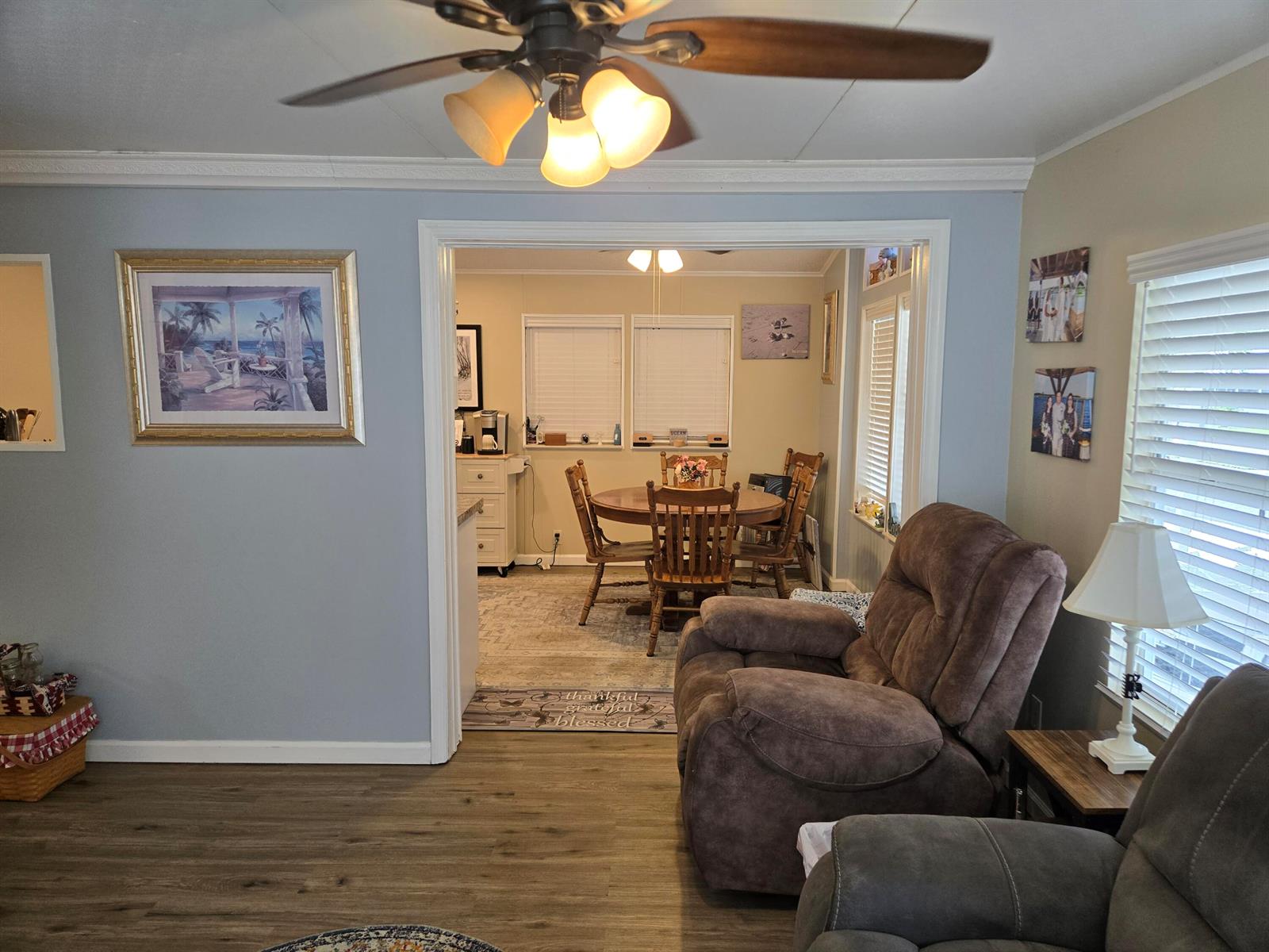 A living room with a brown recliner opens into a dining area with a wooden table — 12240 SE 138th Boulevard # 225, Okeechobee FL 34974, OKEECHOBEE, FL