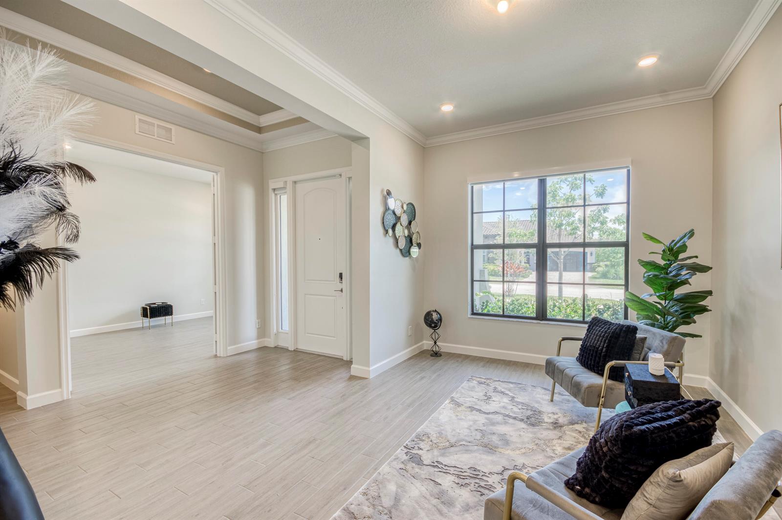 A bright entryway features light wood-look tile flooring, a white front door, and two armchairs — 19077 Fly Rod Run, FL 33470, FL