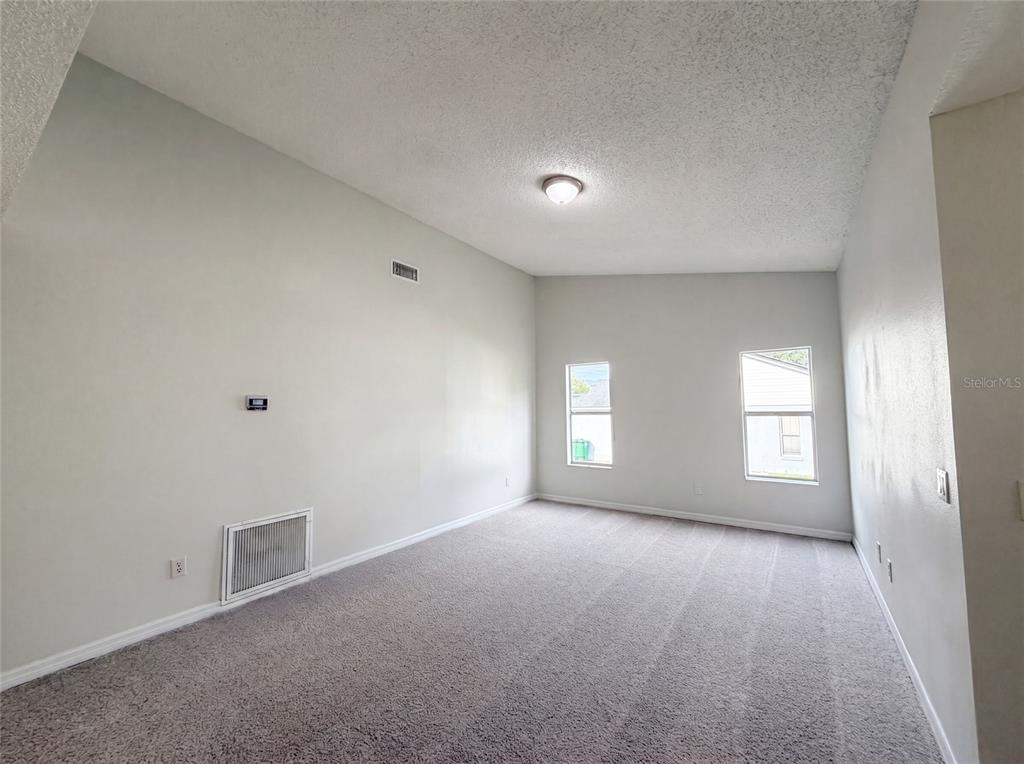 An empty room with gray carpet, light-colored walls, two windows, and a ceiling light fixture — 3143 BOXELDER STREET, DELTONA, FL