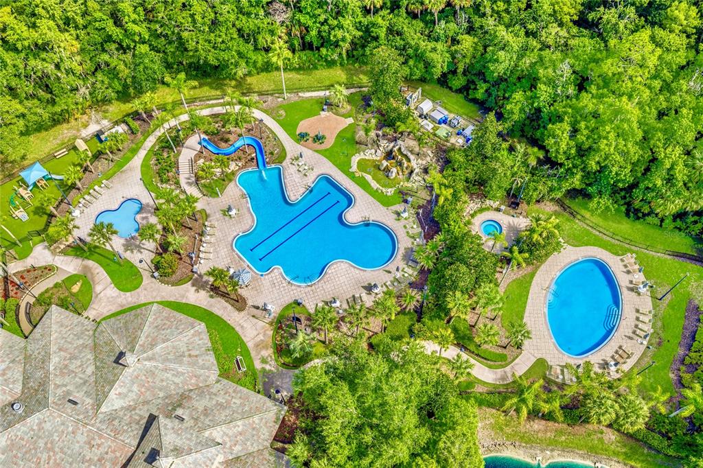 An aerial view shows a community pool area with a waterslide, spa, and surrounding landscaping — 5125 PALM SPRINGS BOULEVARD UNIT 1204, TAMPA, FL
