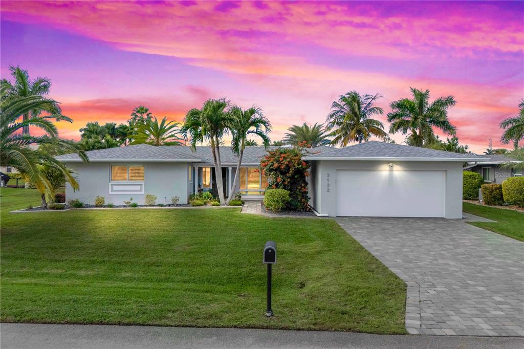 A single-story house with a white garage, gray roof, and palm trees under a sunset — 3122 SE 18TH PLACE, CAPE CORAL, FL