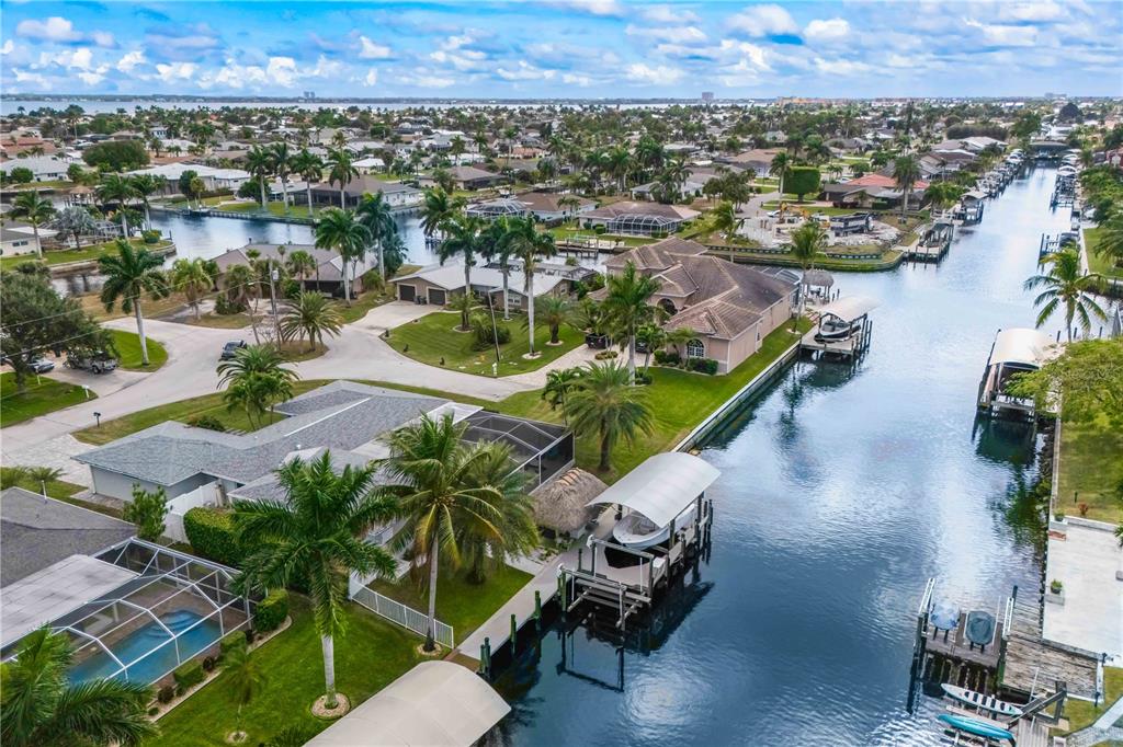 An aerial view shows waterfront homes with boat docks and swimming pools along a canal — 3122 SE 18TH PLACE, CAPE CORAL, FL
