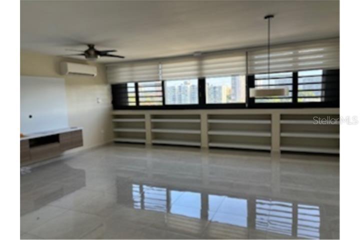 A living room with light tile floors, built-in shelving, a ceiling fan, and large windows — D-10 MANSIONES DE GARDEN HILLS UNIT D-10, GUAYNABO, PR