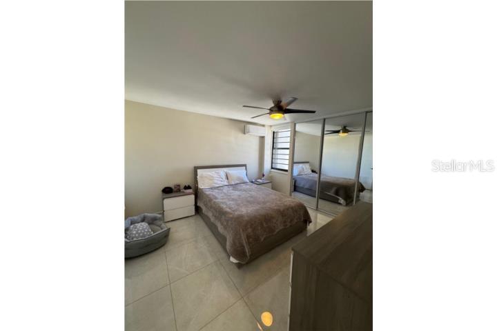 A bedroom with a bed, mirrored closet doors, tile flooring, and a ceiling fan — D-10 MANSIONES DE GARDEN HILLS UNIT D-10, GUAYNABO, PR