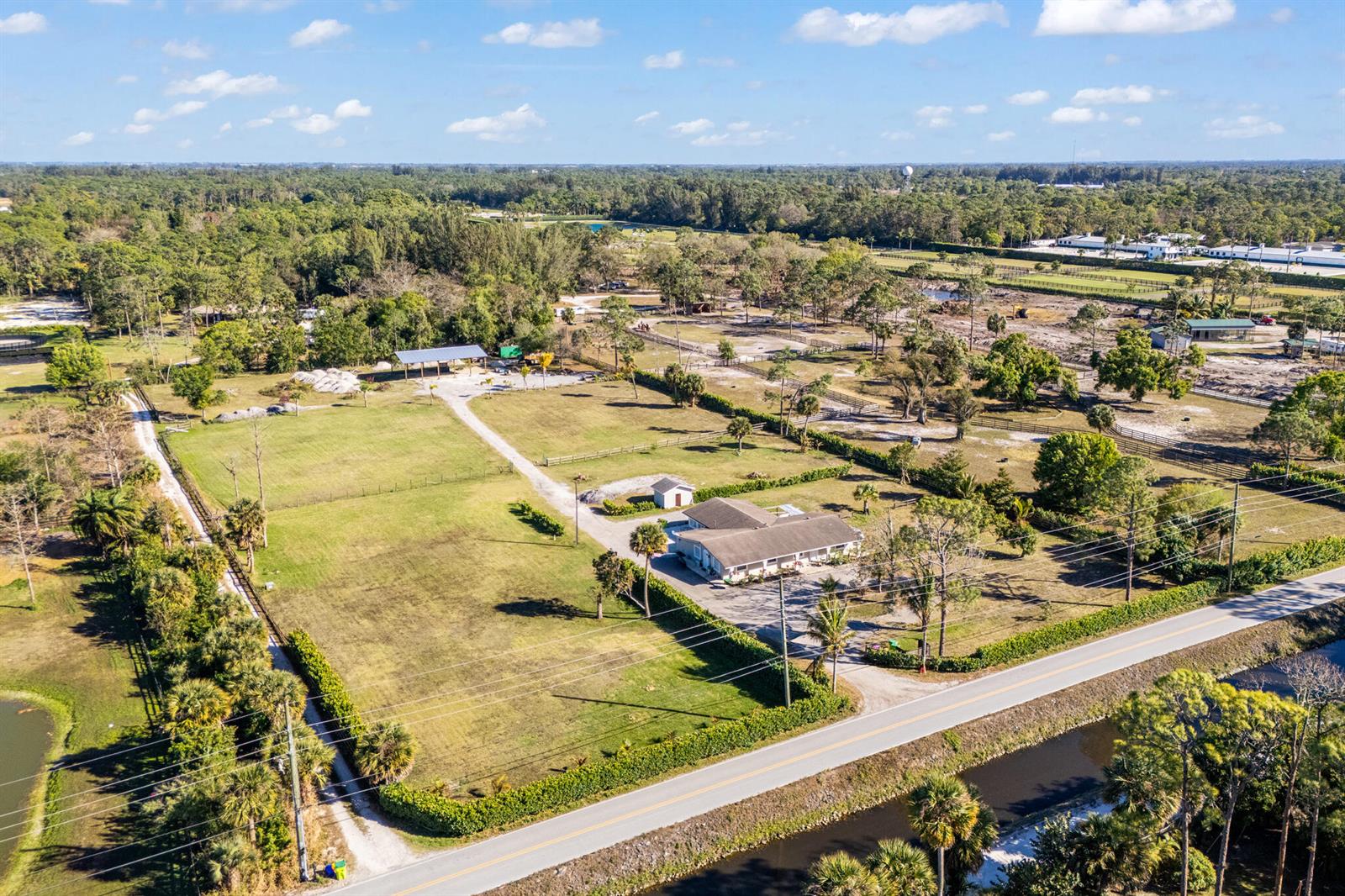 An aerial view shows a house with a large yard, outbuildings, and a roadside canal — 1216 C Road, FL 33470, FL