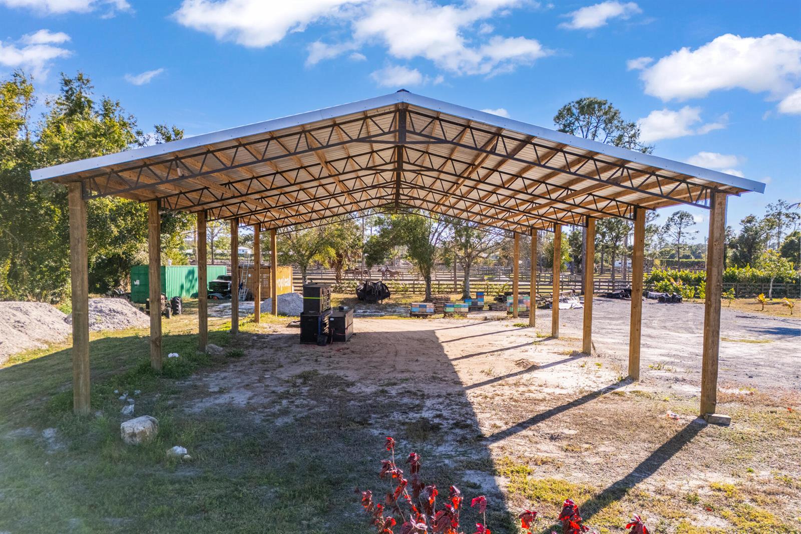 An open-air metal pole barn structure stands on a dirt lot under a blue sky — 1216 C Road, FL 33470, FL