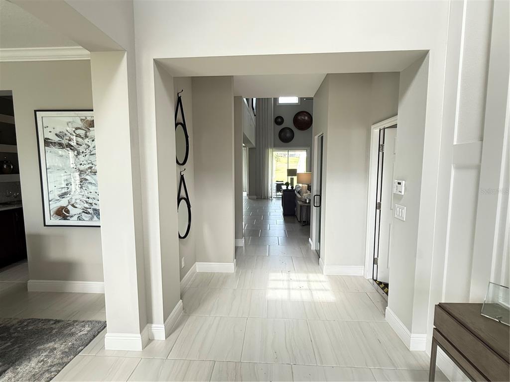 A bright entryway with light tile flooring leads into a spacious living area with high ceilings — 7504 CATANIA LOOP, CLERMONT, FL