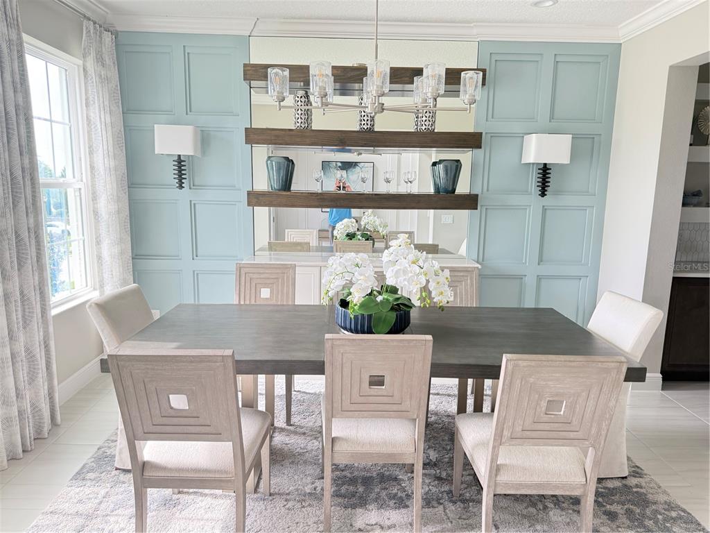 A dining room features a dark wood table, light-colored chairs, and blue paneled accent walls — 7504 CATANIA LOOP, CLERMONT, FL