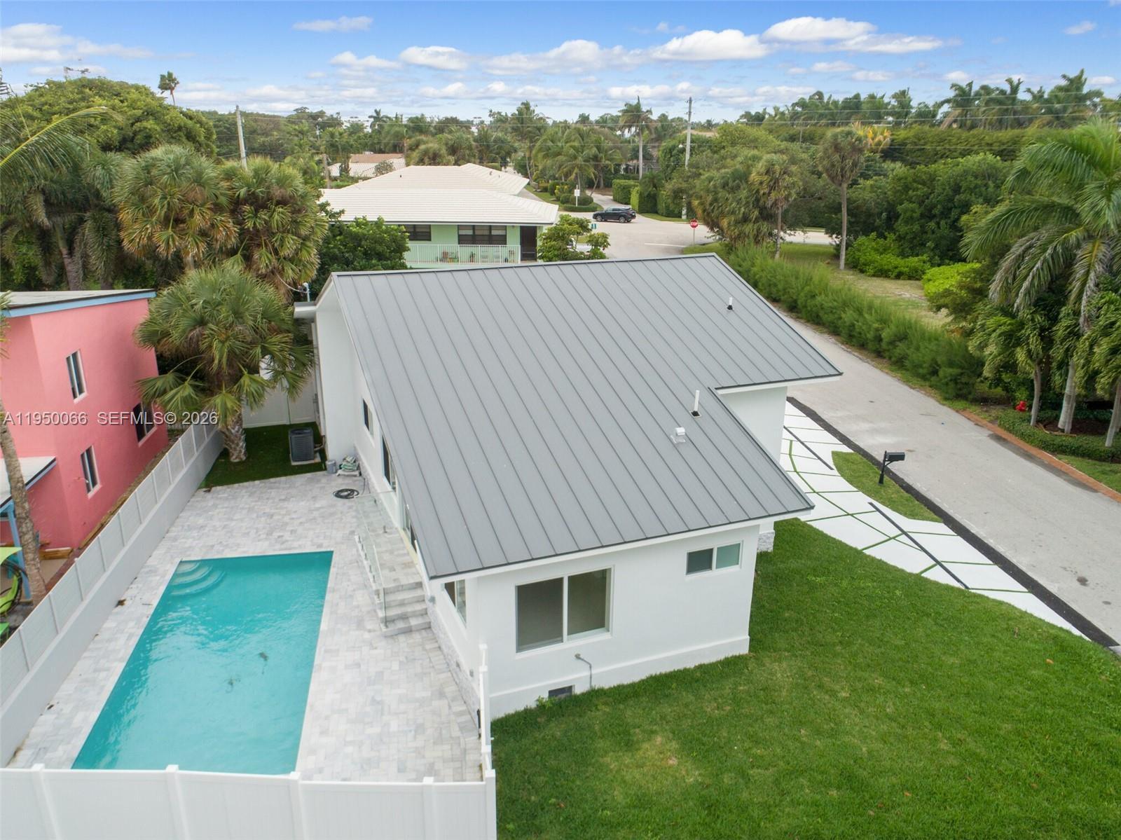 An aerial view shows a white house with a metal roof, pool, and paved patio — 12 Adams Road, Ocean Ridge FL 33435, OCEAN RIDGE, FL