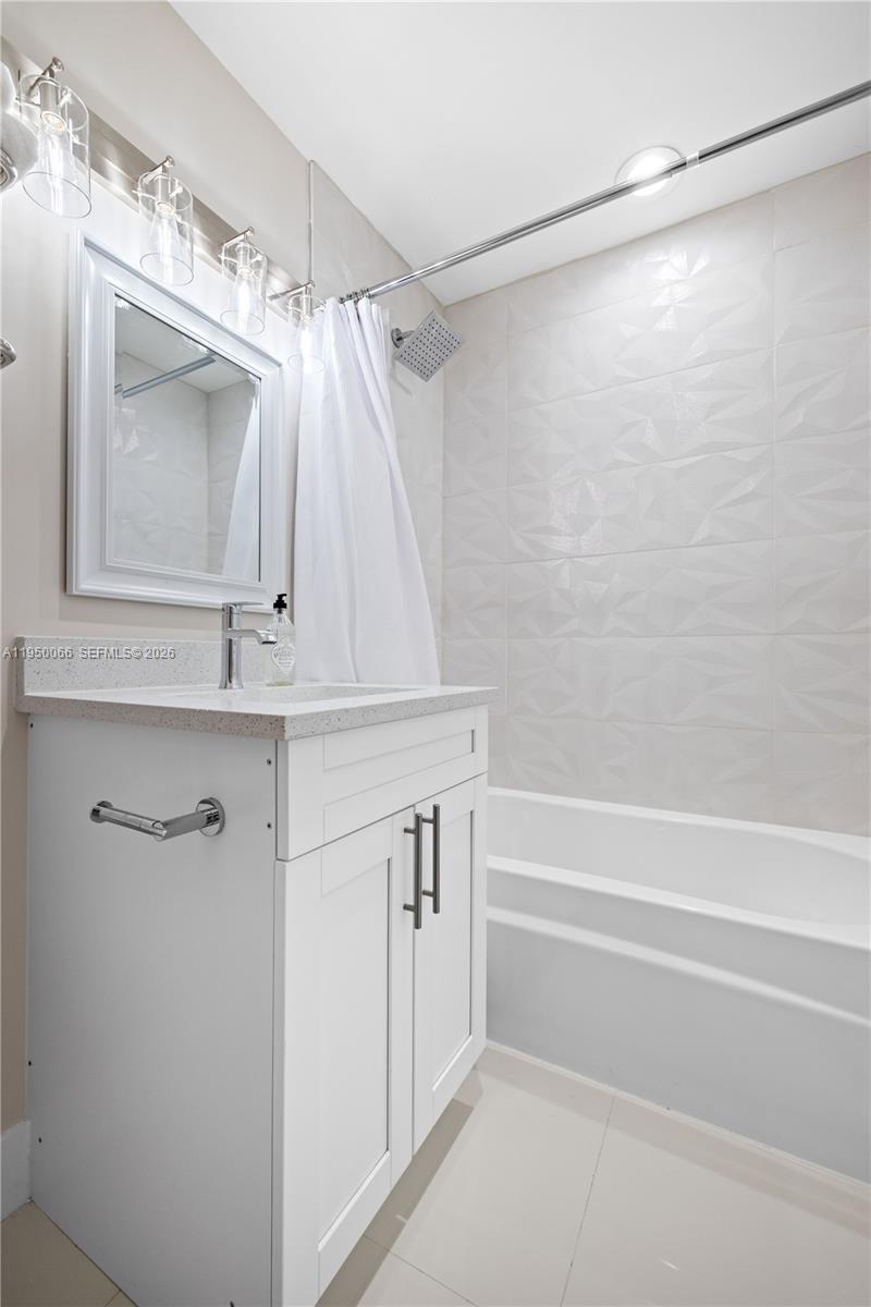 A bathroom features a white vanity, a mirror, and a tub with textured wall tiles — 12 Adams Road, Ocean Ridge FL 33435, OCEAN RIDGE, FL