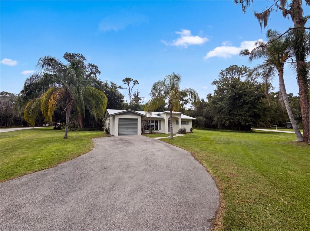 A single-story house with a gray garage and palm trees sits on a large lawn — 6309 SHERMAN TERRACE, SEBRING, FL