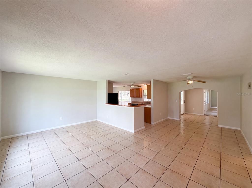 An open-concept living and dining area features light-colored tile flooring and a kitchen pass-through — 6309 SHERMAN TERRACE, SEBRING, FL