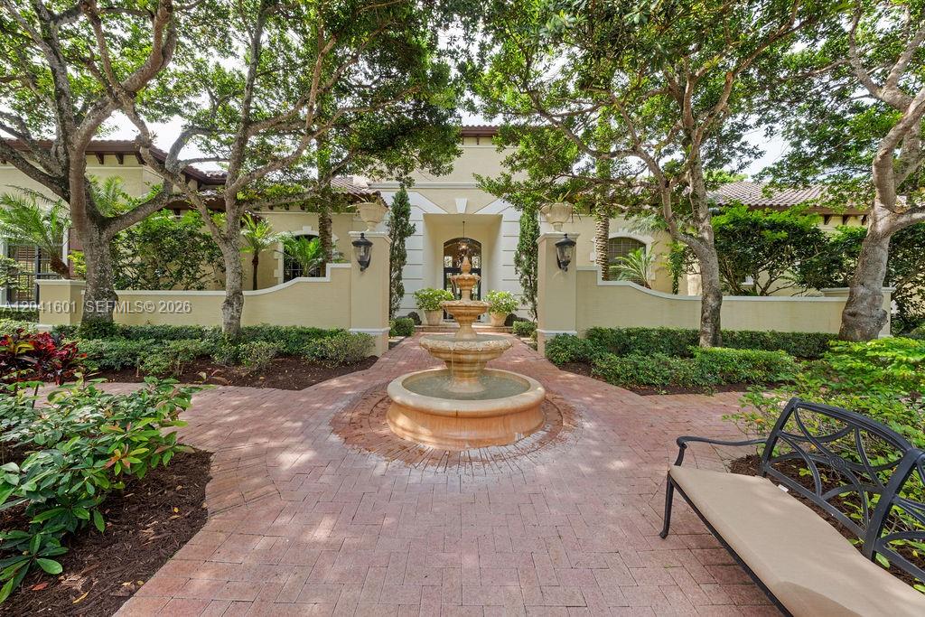 A stone fountain sits in the center of a brick courtyard leading to a house entrance — 9001 SW 59th Ct, Pinecrest FL 33156, PINECREST, FL