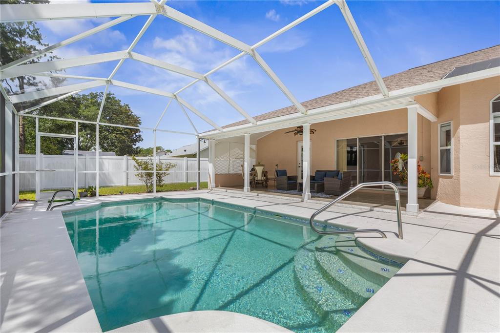 A screened-in swimming pool with steps and a covered patio area behind a residential home — 137 WYNNFIELD DRIVE, PALM COAST, FL