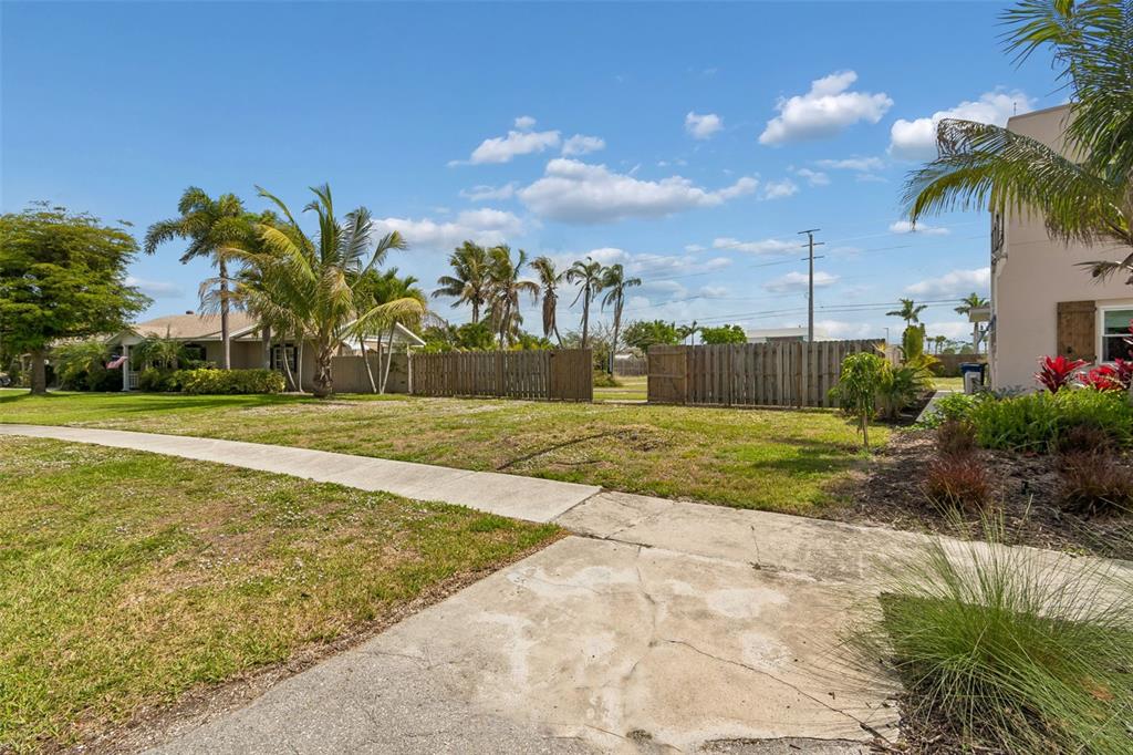 A grassy vacant lot sits between two houses with a sidewalk in the foreground — 603 CASABELLA DRIVE, BRADENTON, FL