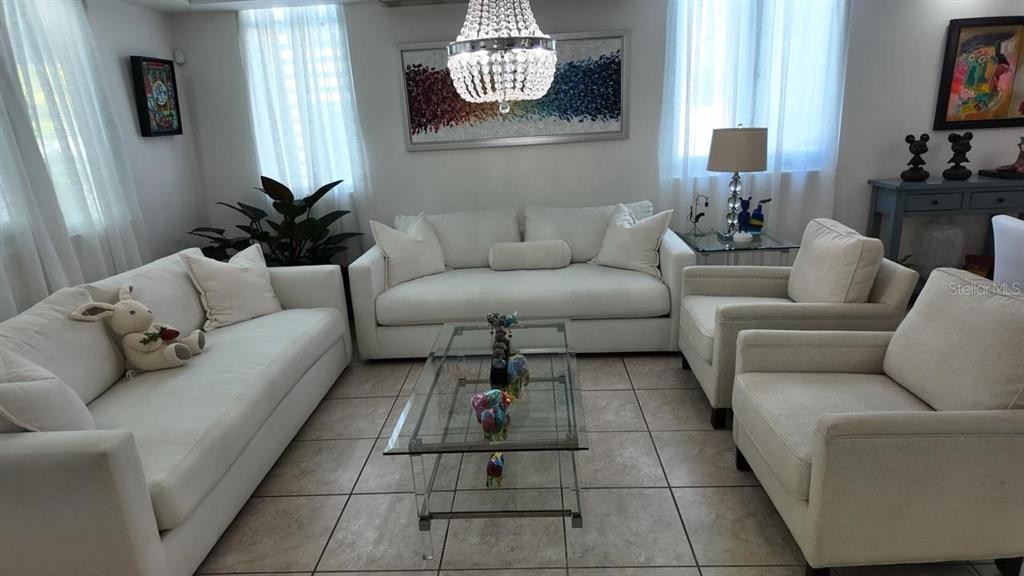 A living room features white sofas, armchairs, a glass coffee table, and a crystal chandelier — 623 MAR DE BERING, DORADO, PR