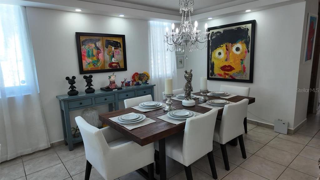 A dining room features a wooden table, white chairs, a chandelier, and colorful wall art — 623 MAR DE BERING, DORADO, PR