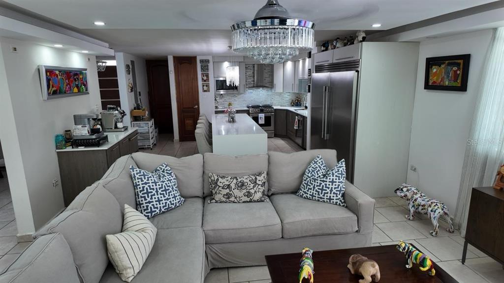 A living room with a sectional sofa opens to a modern kitchen with an island — 623 MAR DE BERING, DORADO, PR