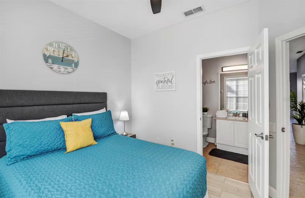 A bedroom with a blue bedspread and a doorway leading to an attached bathroom — 8117 PRINCESS PALM, KISSIMMEE, FL