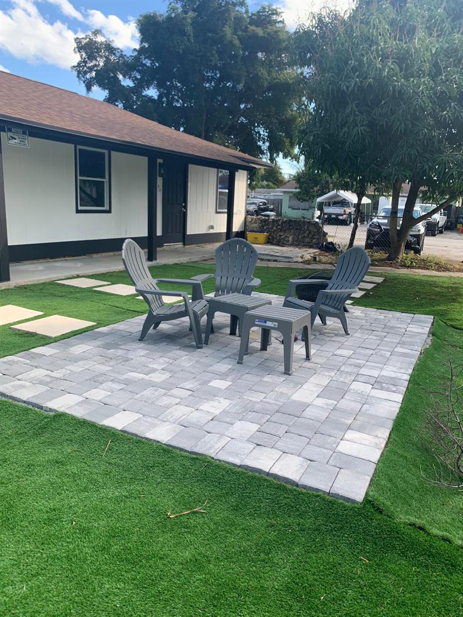 A gray paver patio with three chairs and a small table sits on a lawn — 3195 Mcsherry Drive S # 3195, Lake Worth FL 33461, LAKE WORTH, FL