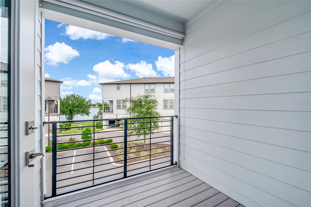 A balcony with gray composite decking, a black metal railing, and white horizontal siding — 12574 WILLSTATTER AVENUE, ORLANDO, FL