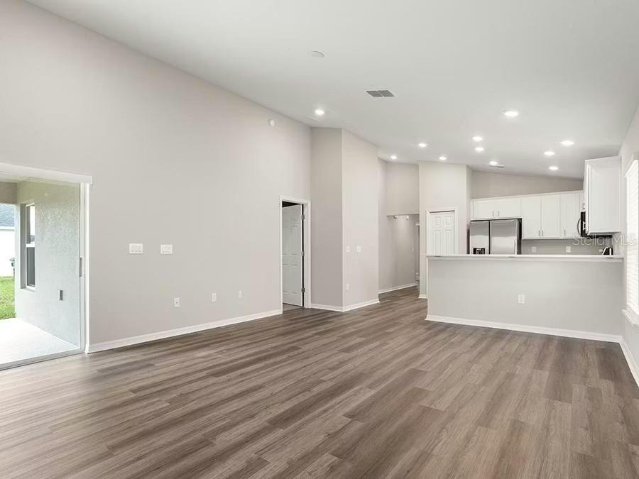 An open-concept living room with light gray walls, wood-look flooring, and a kitchen breakfast bar — 5125 SYLAS JAX AVENUE, WINTER HAVEN, FL