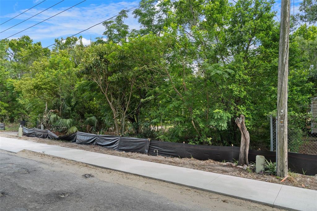 A vacant, wooded lot features a new concrete sidewalk and black silt fencing — 7039 JOHNSON ROAD, PORT RICHEY, FL